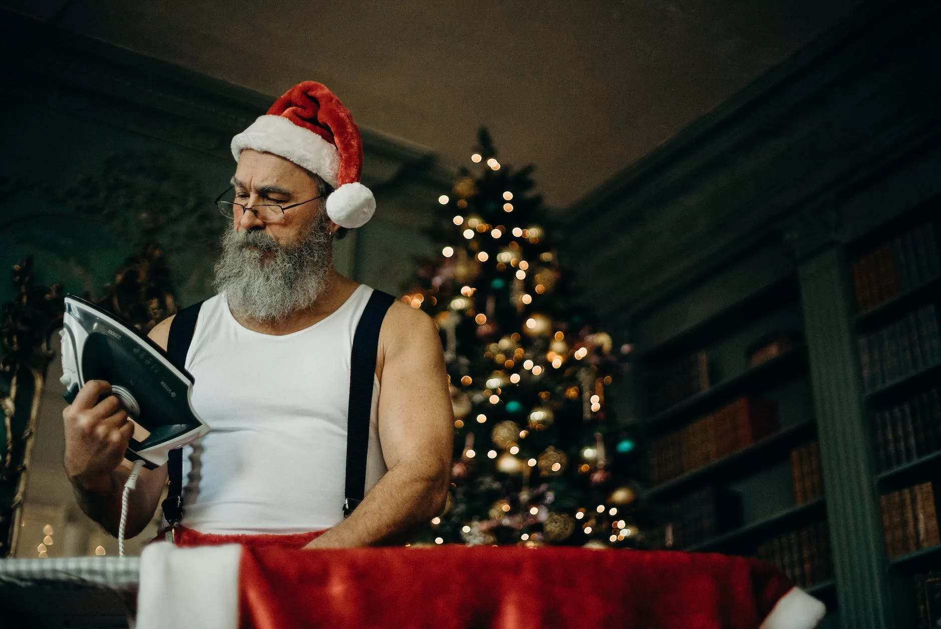 man in white tank wearing santa hat holding black and gray dry iron