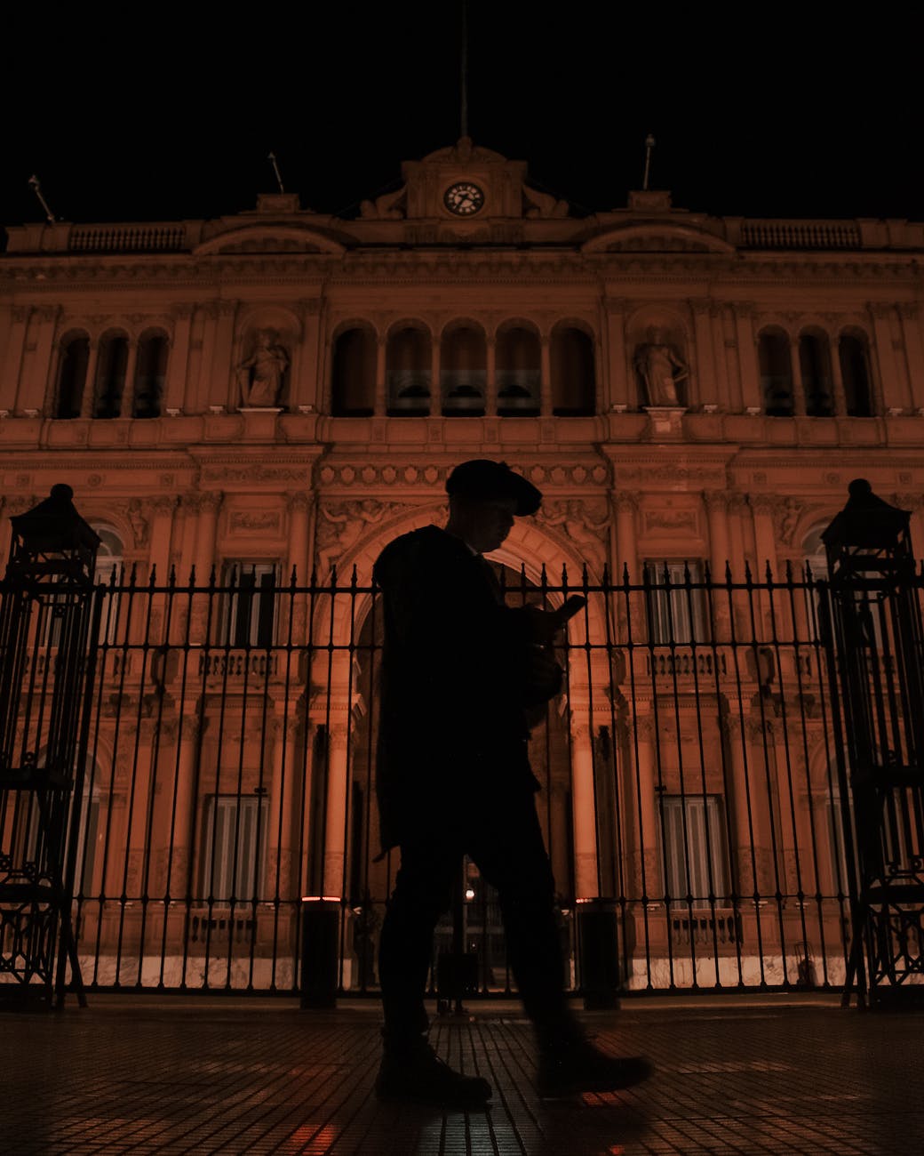 man walking beside a metal fence