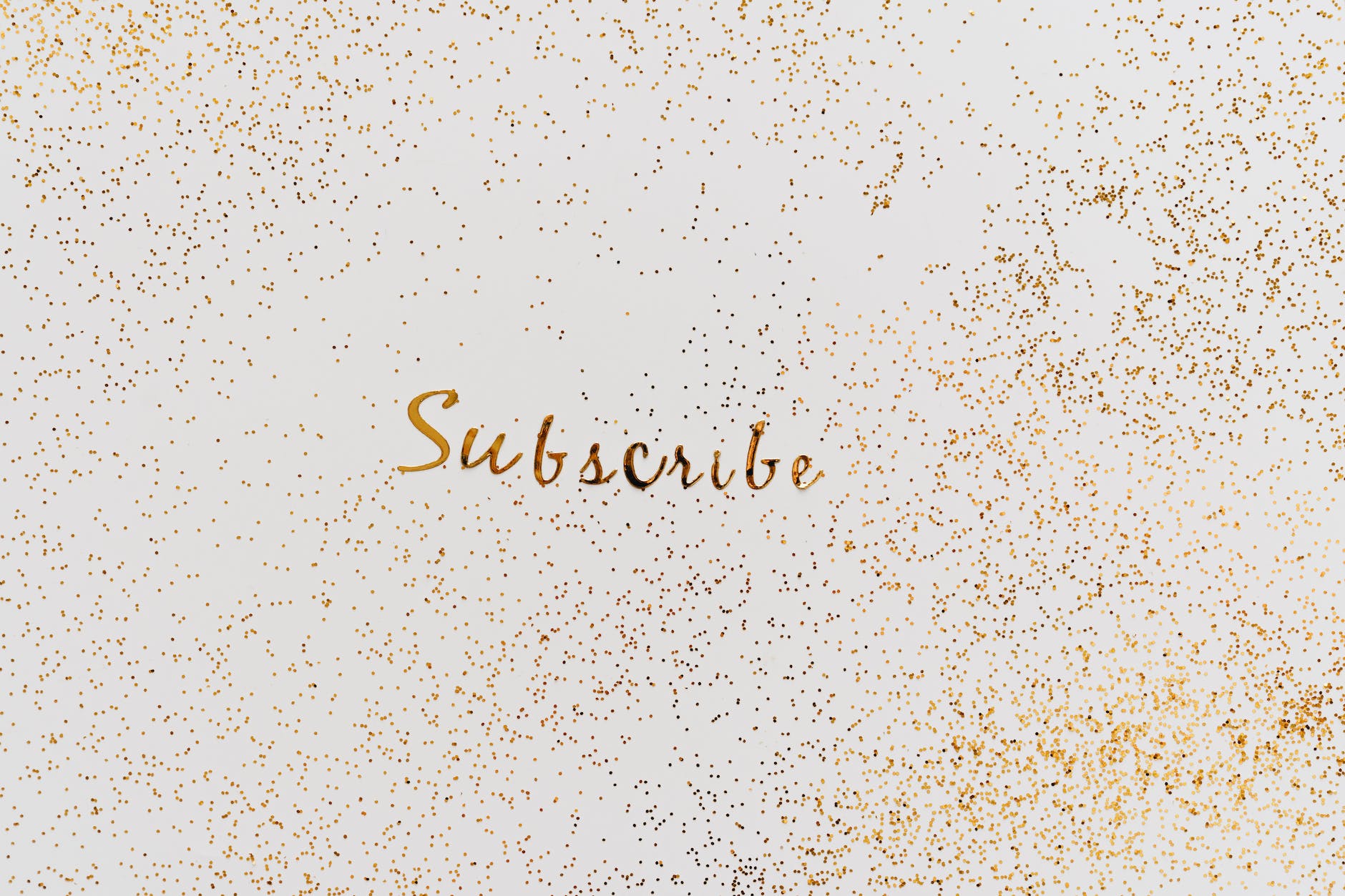 a word subscribe in gold color decorated with scattered glitters