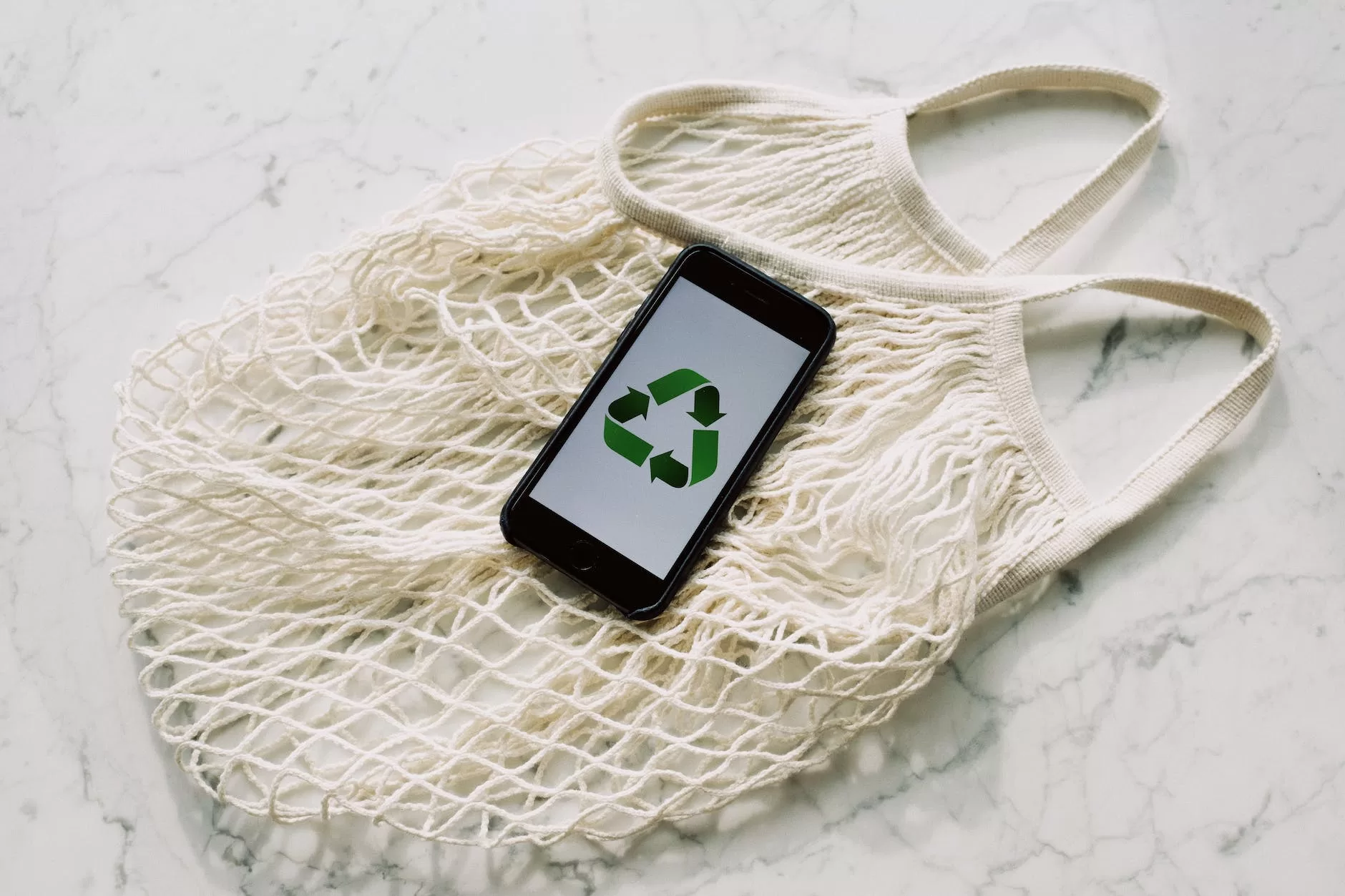mobile phone with green recycling sign and mesh bag sustainability in Iceland
