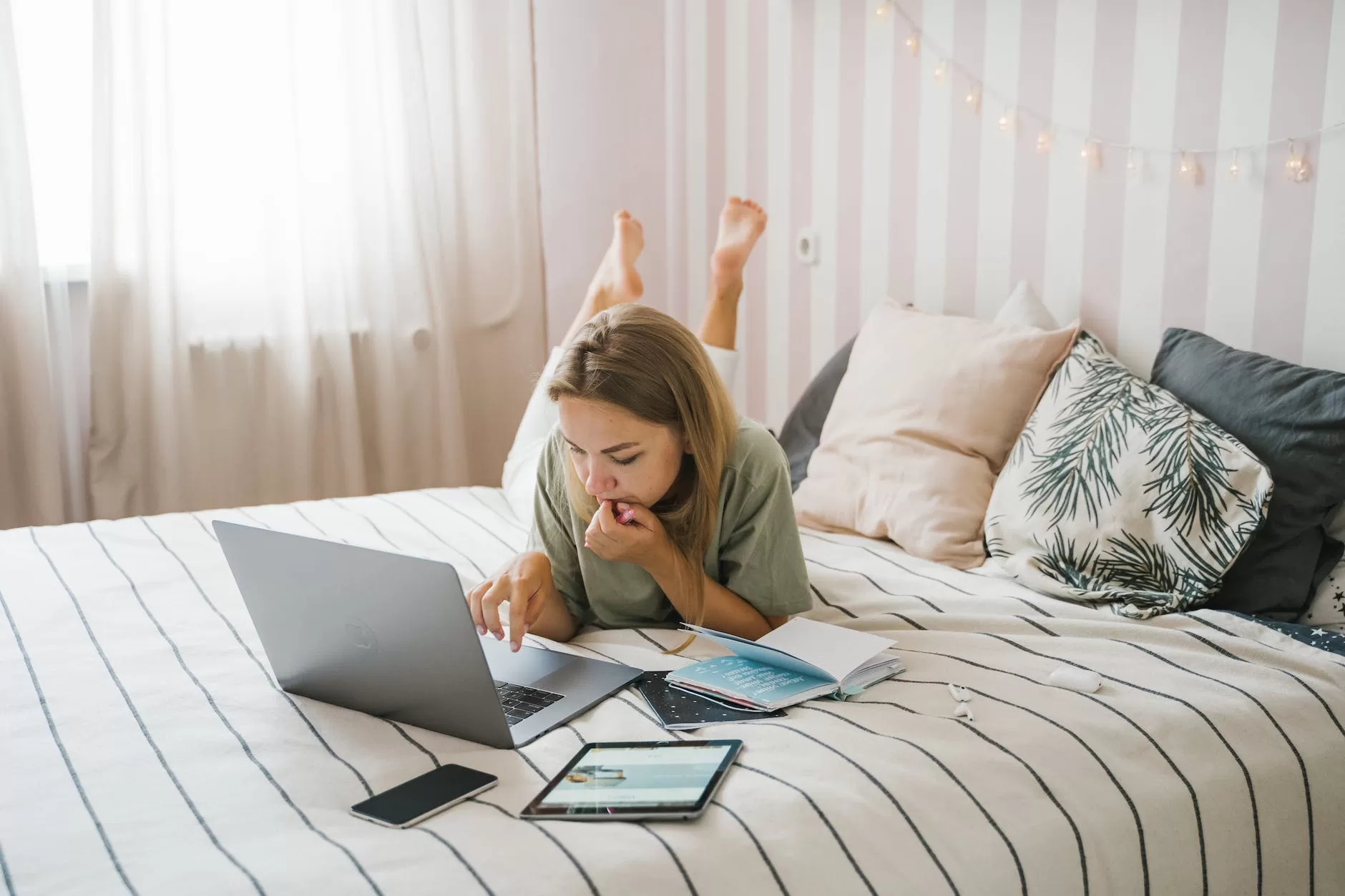 woman lying on bed while using a laptop