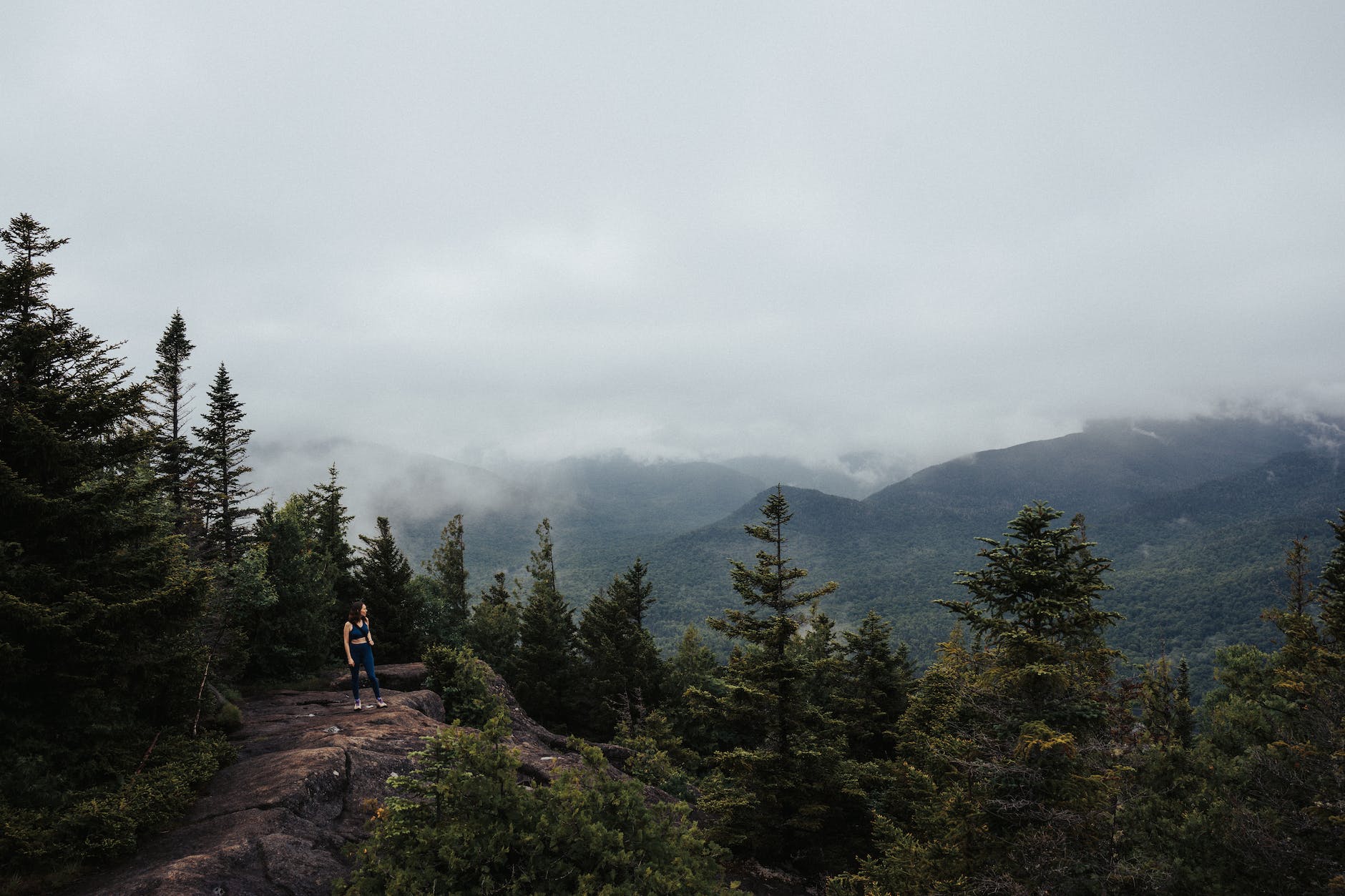 woman on hilltop over forest under clouds