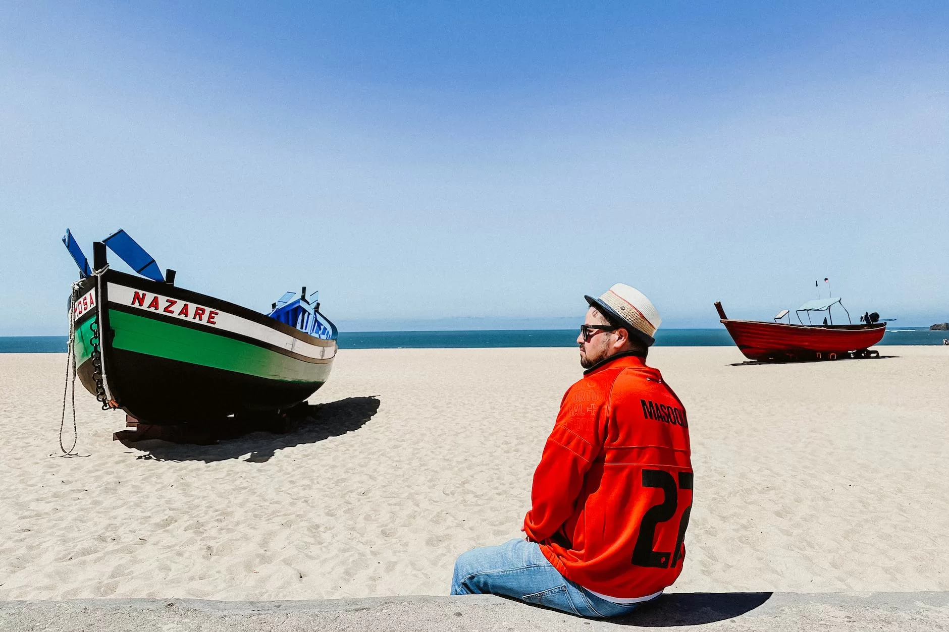 man sitting on the beach in nazare portugal