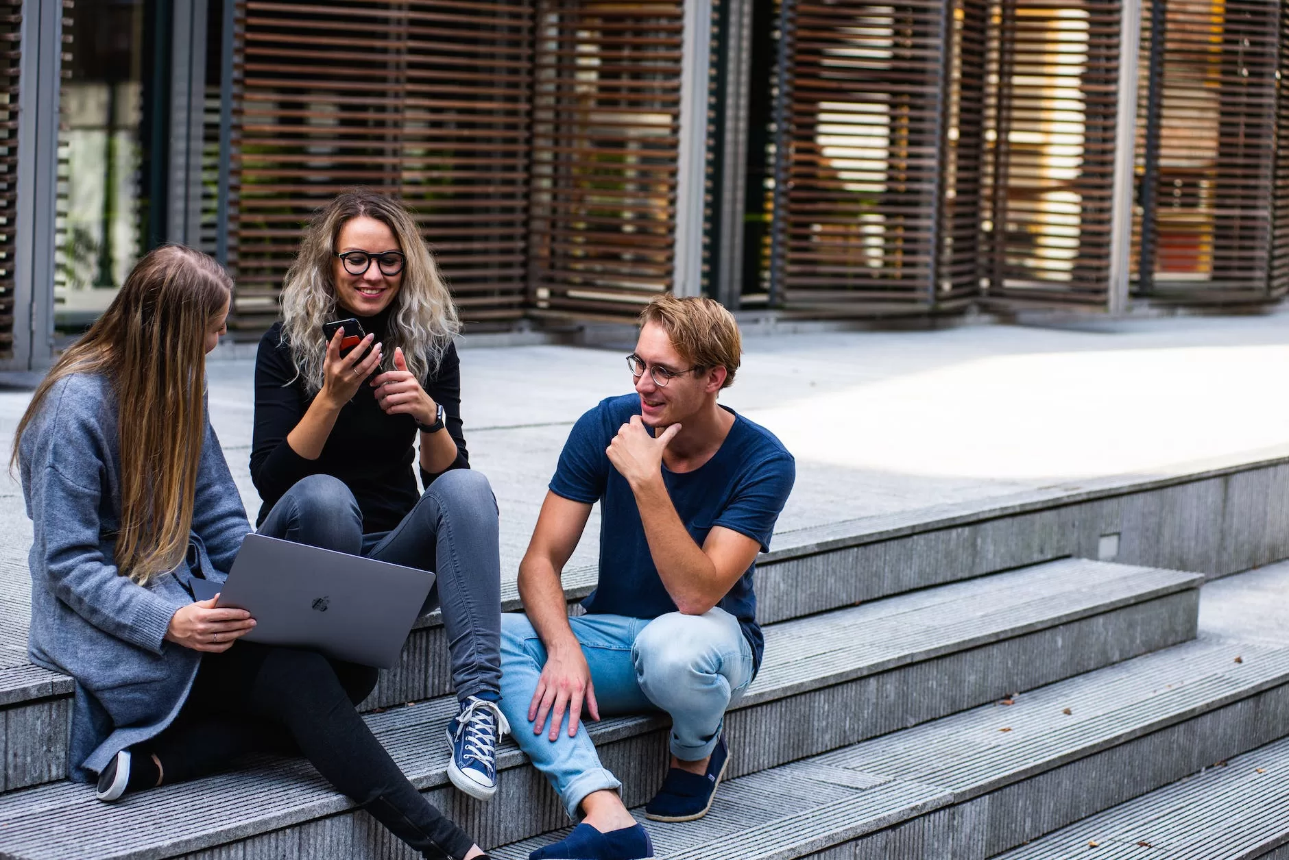 three persons sitting on the stairs talking with each other. Student discounts can get you cheap flights