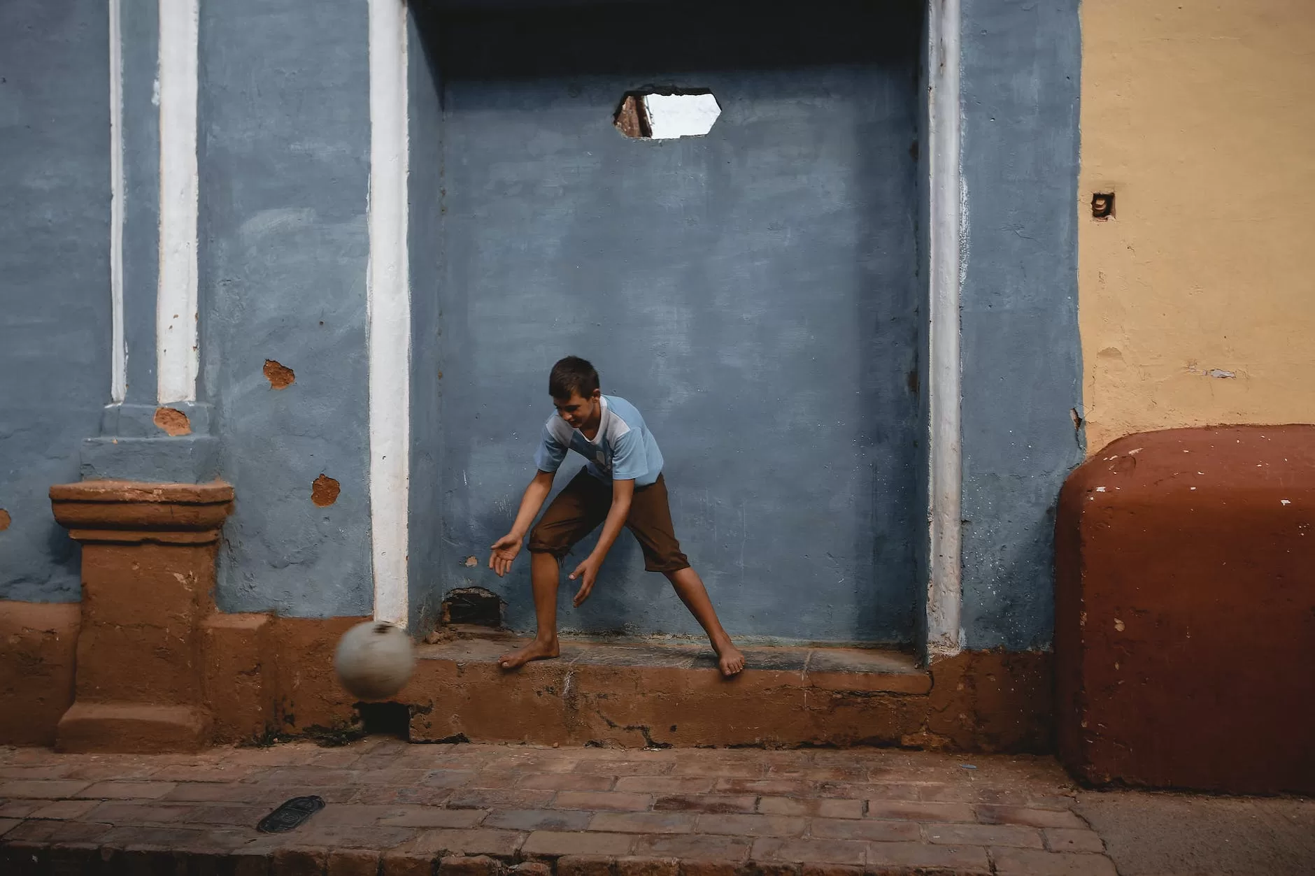 a boy playing a ball in a building niche