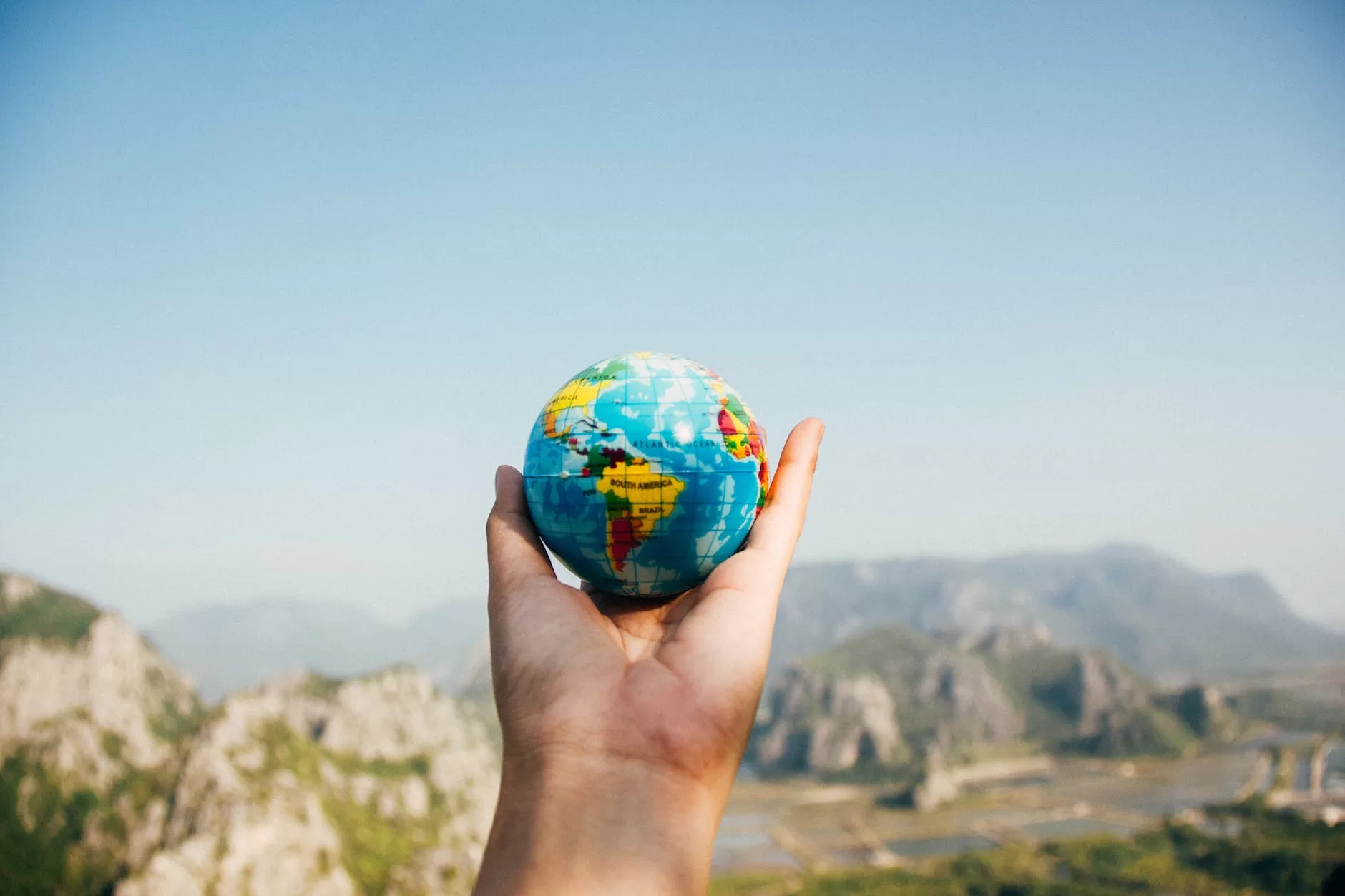 How to start a travel blog? person holding world globe facing mountain