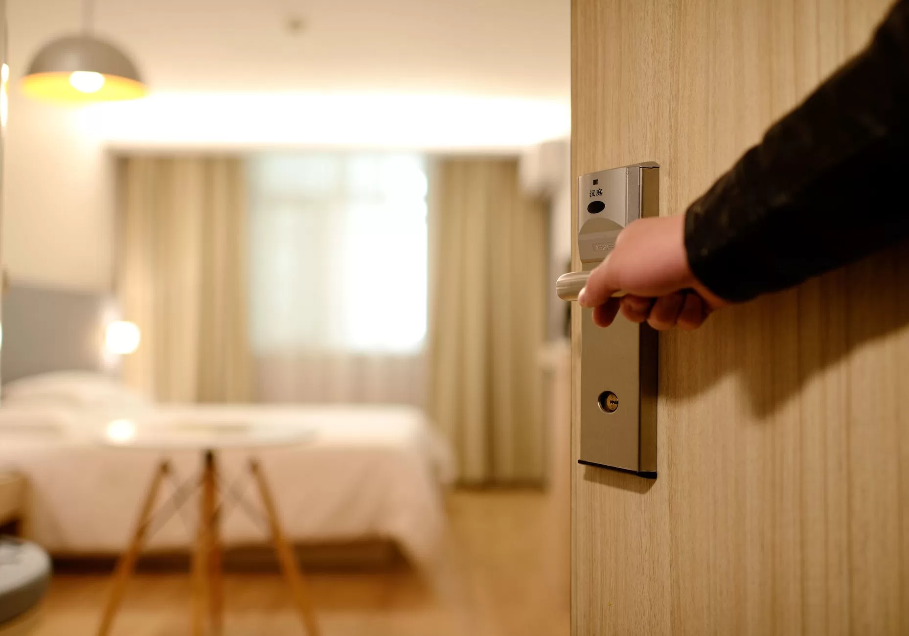 person holding on door lever inside room