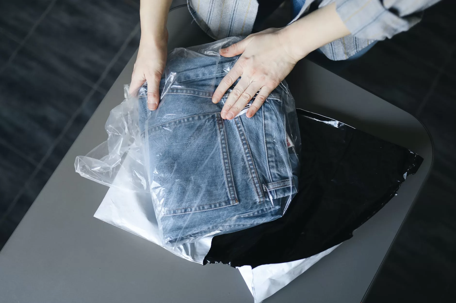 woman packing jeans into plastic bag Follow our Packing Guide.
