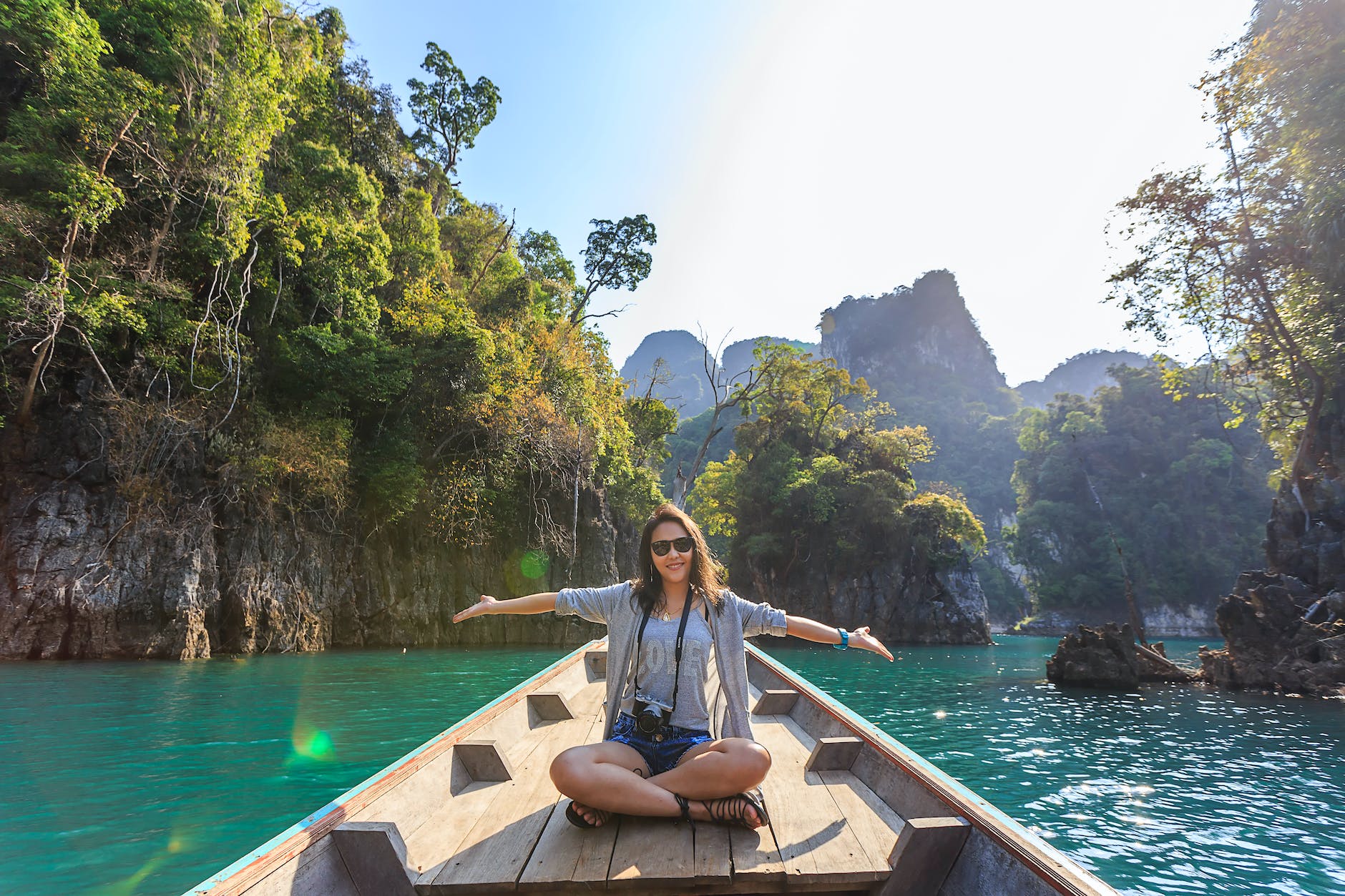 solo female travel sitting on boat spreading her arms