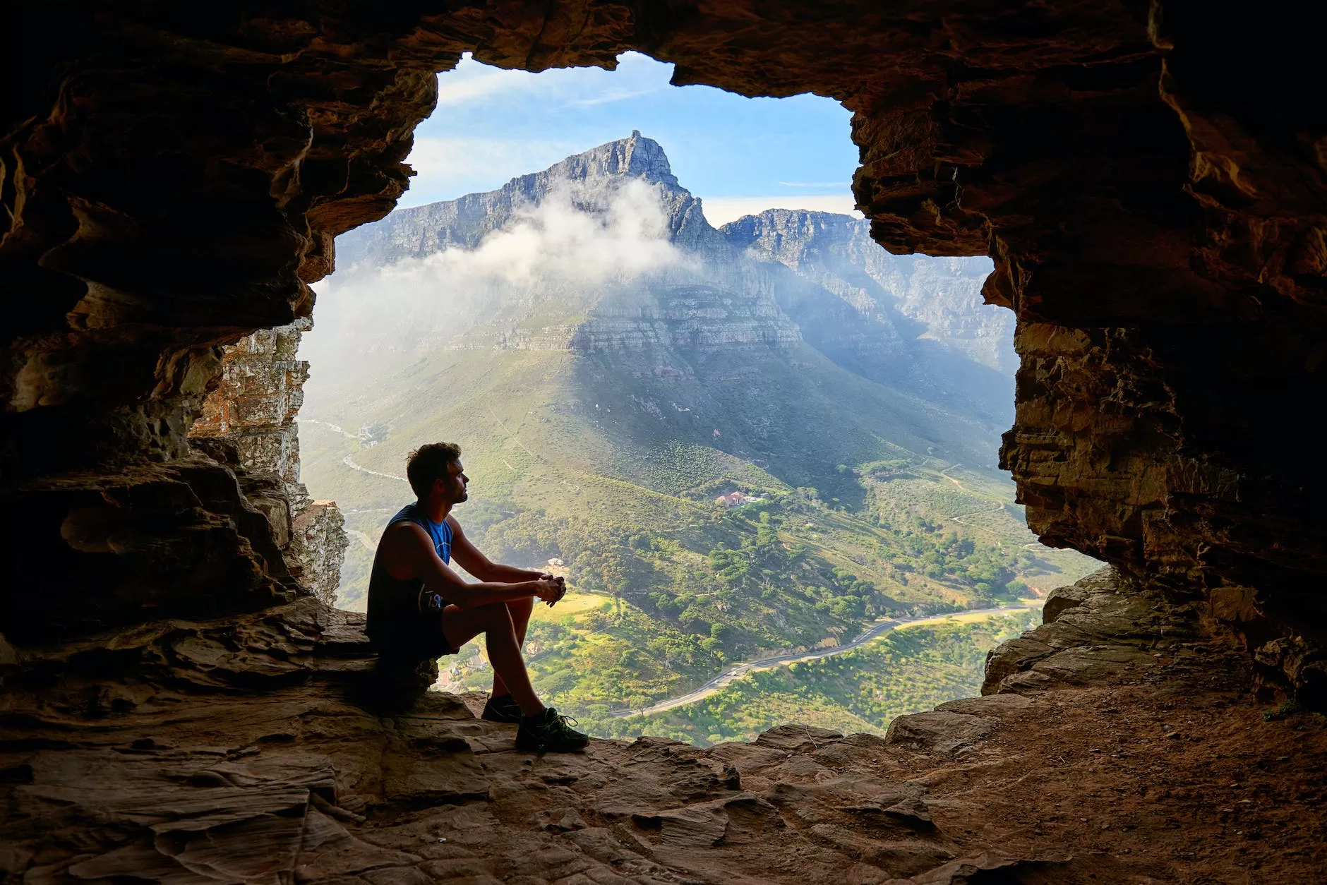 photo of man sitting on a cave ponders how to travel hack your next adventure