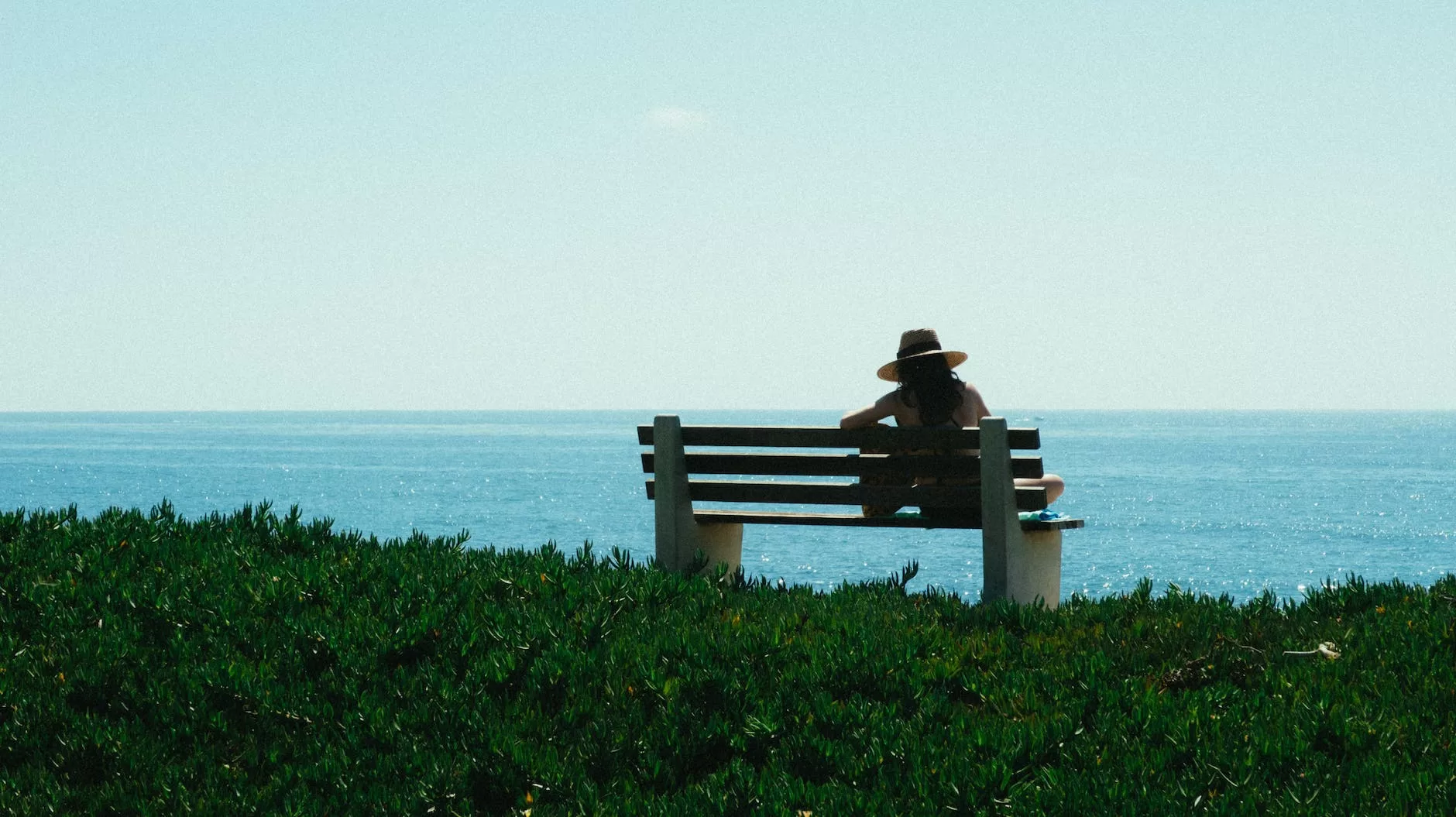 woman sitting on bench on grass shore during day. solo female travel