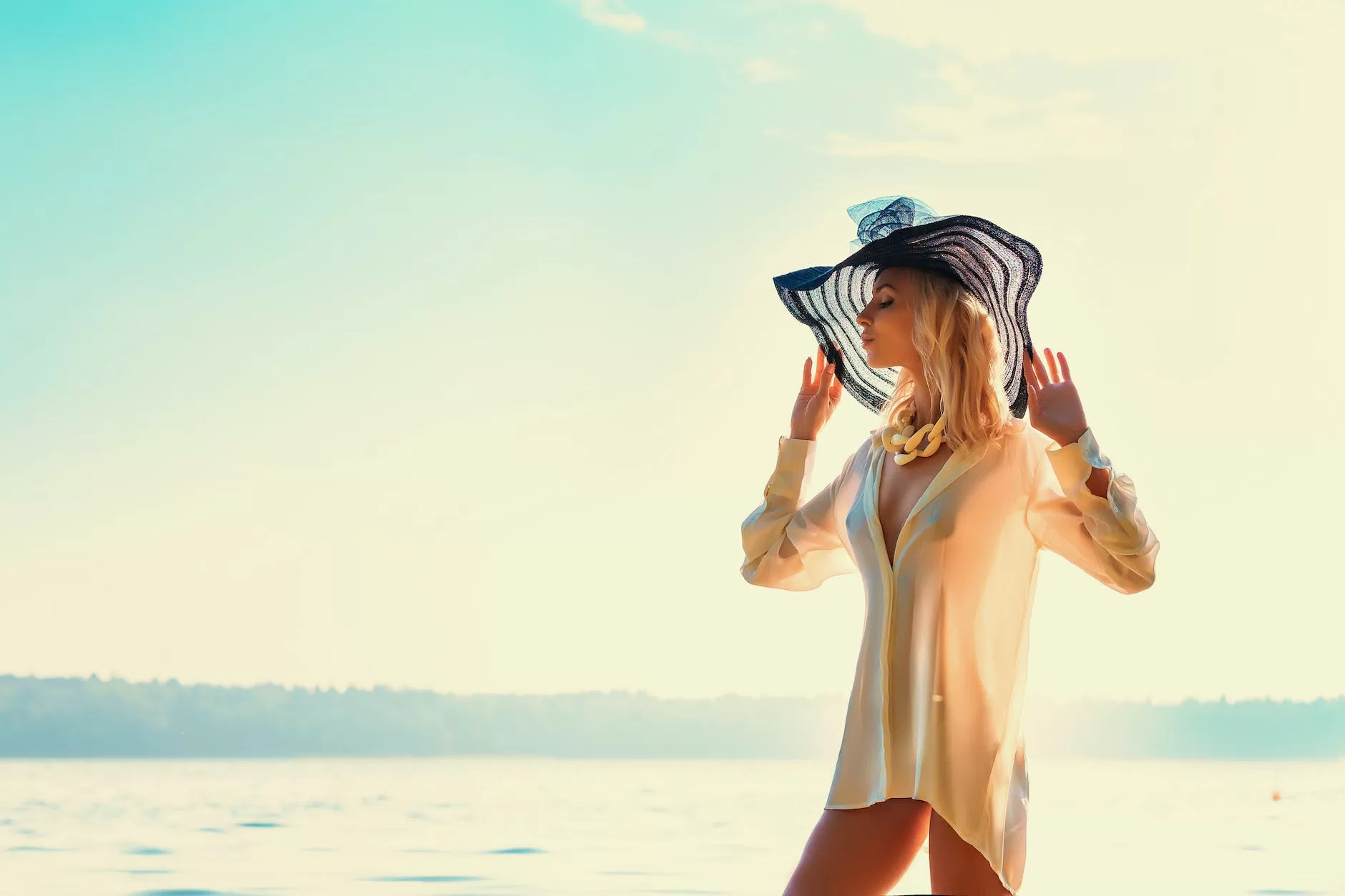stylish sensual woman in hat near sea in sunshine plan a trip
