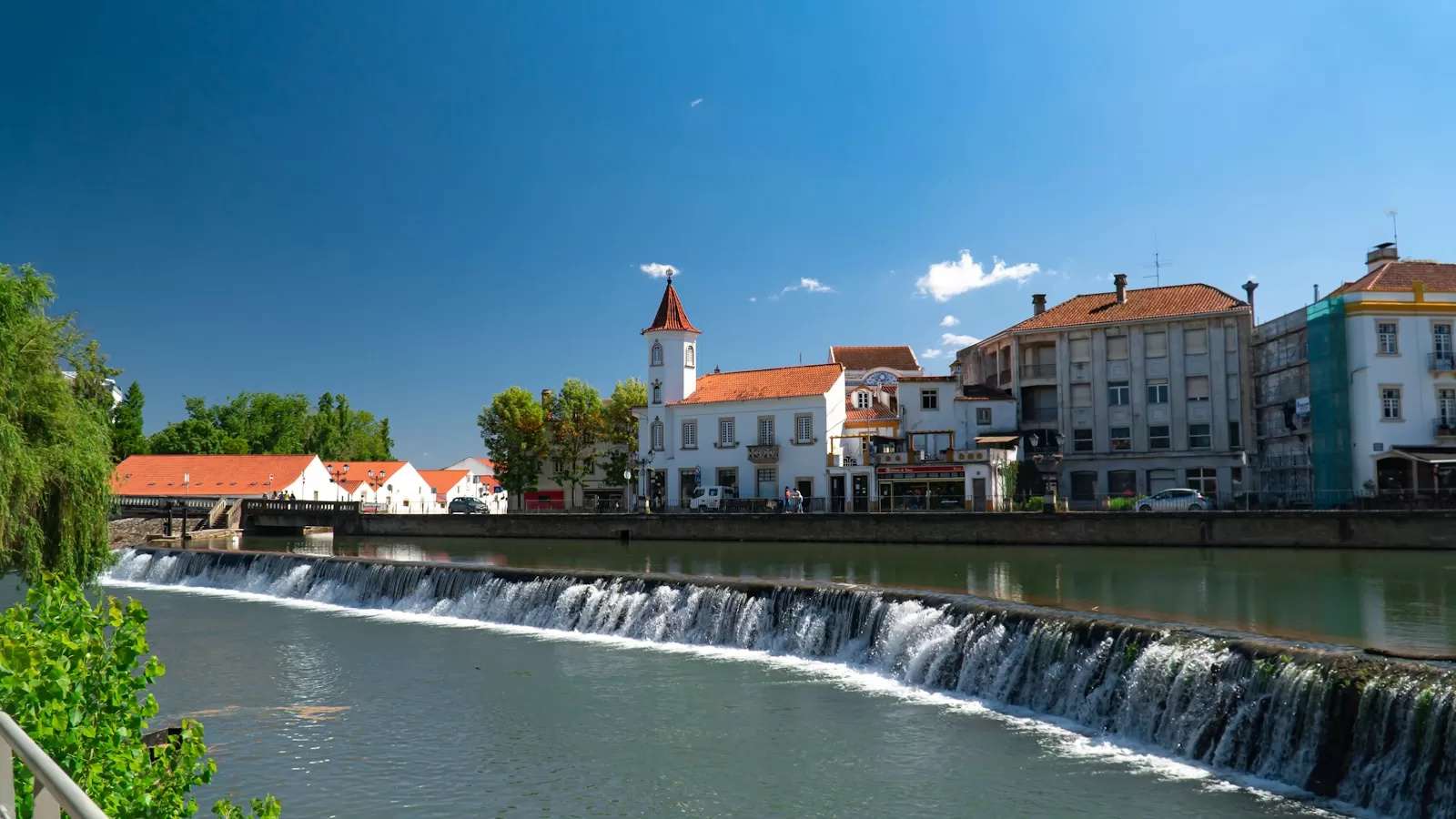 white and brown concrete building near water falls under blue sky during daytime